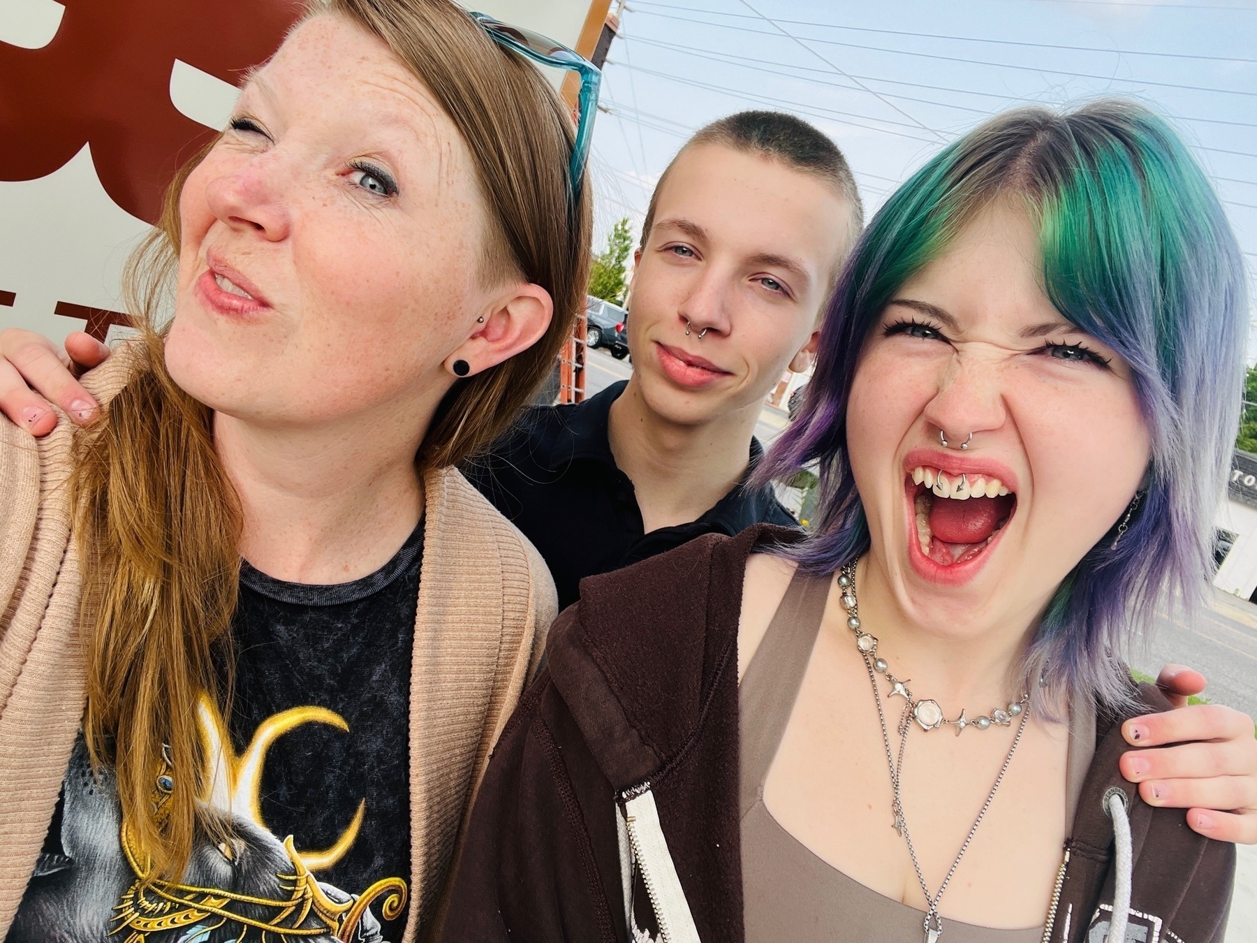 Mom with teenage daughter and teenage son making fierce faces at the camera with fresh piercings